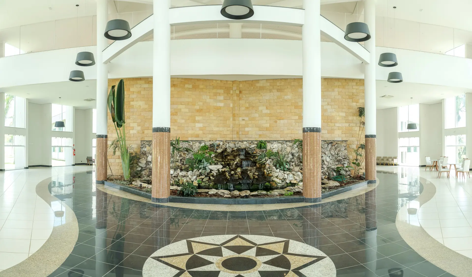 Hall central do Spa Recovery, com pé-direito duplo, jardim de pedras e espelho d'água