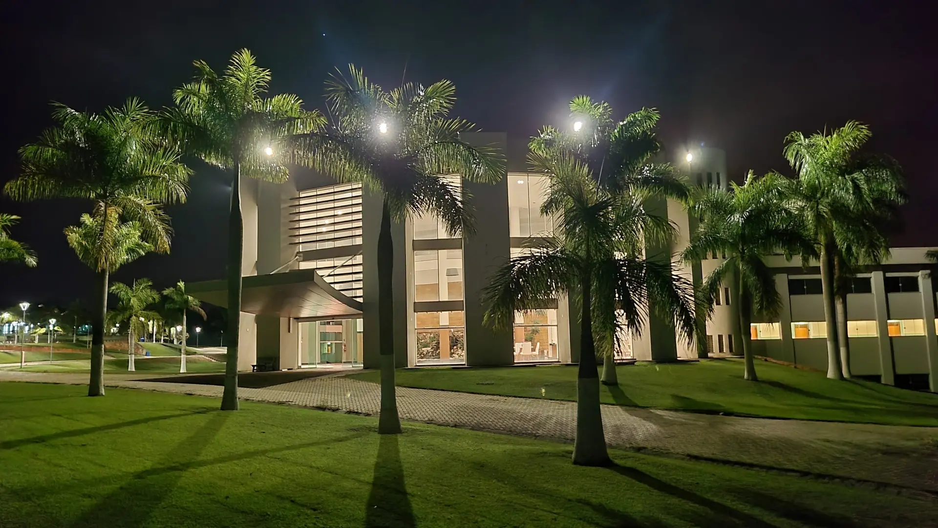 Prédio principal do Spa Recovery iluminado à noite, entre as palmeiras