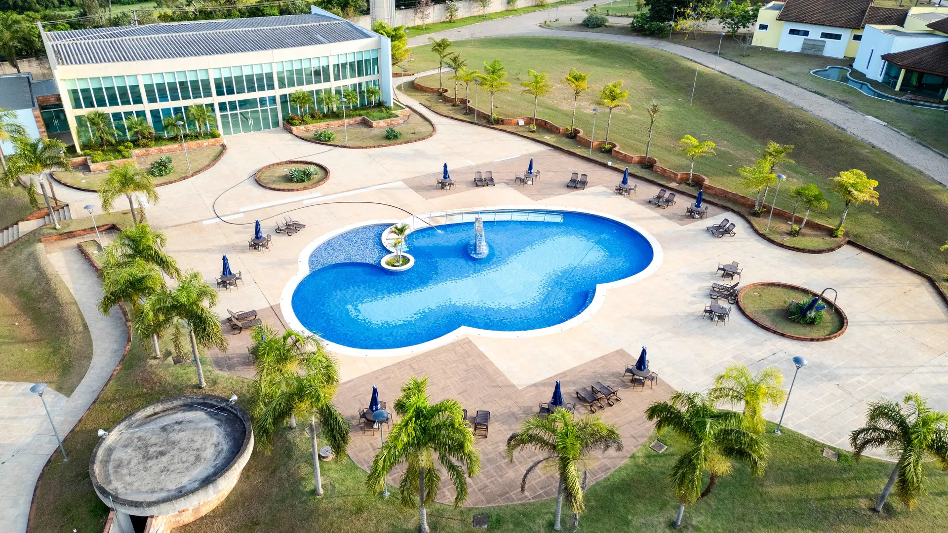 Vista aérea da piscina social do Spa Recovery, com o deck, os guarda-sóis e a mata em volta