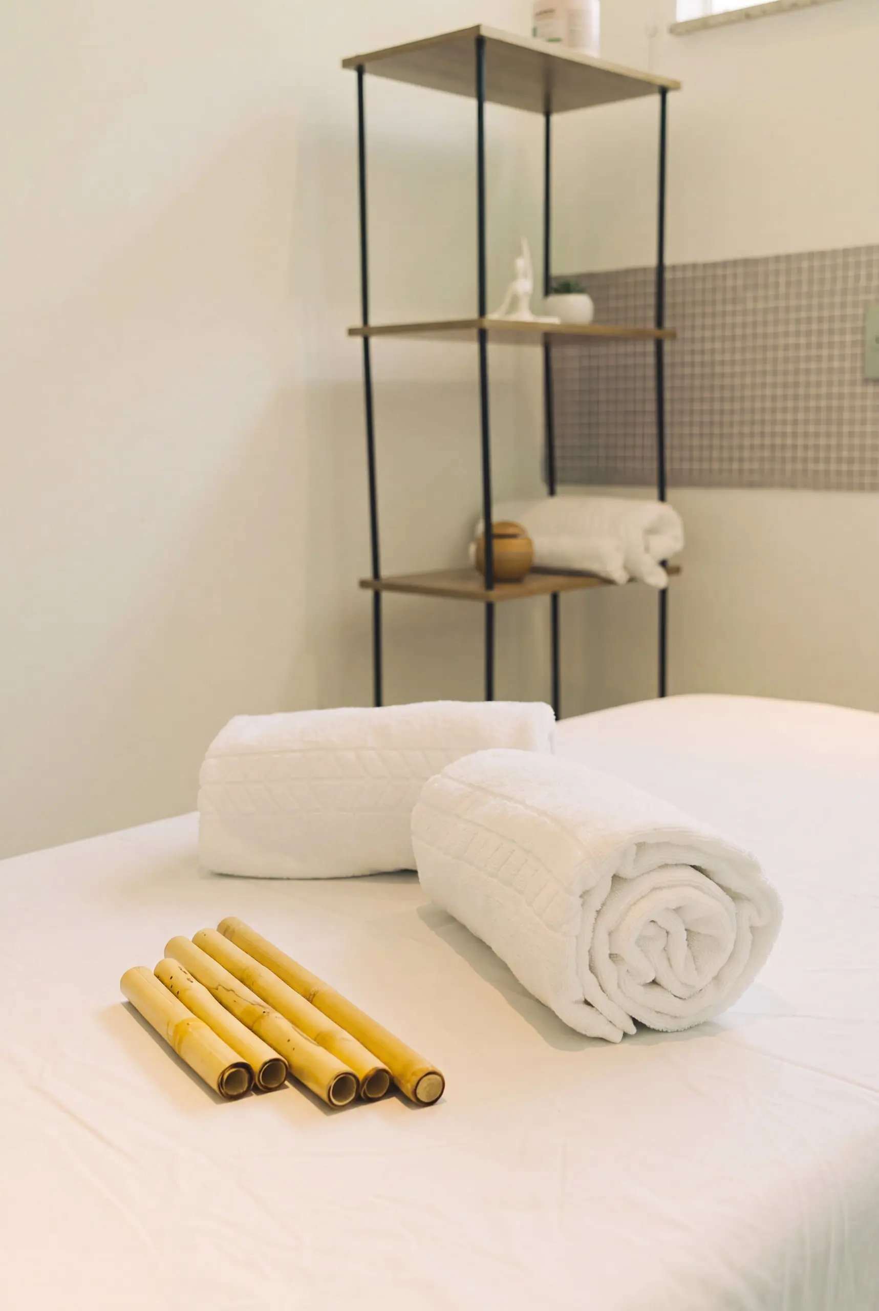 Sala de massagem do Spa Recovery, com maca preparada, toalhas enroladas e bambus
